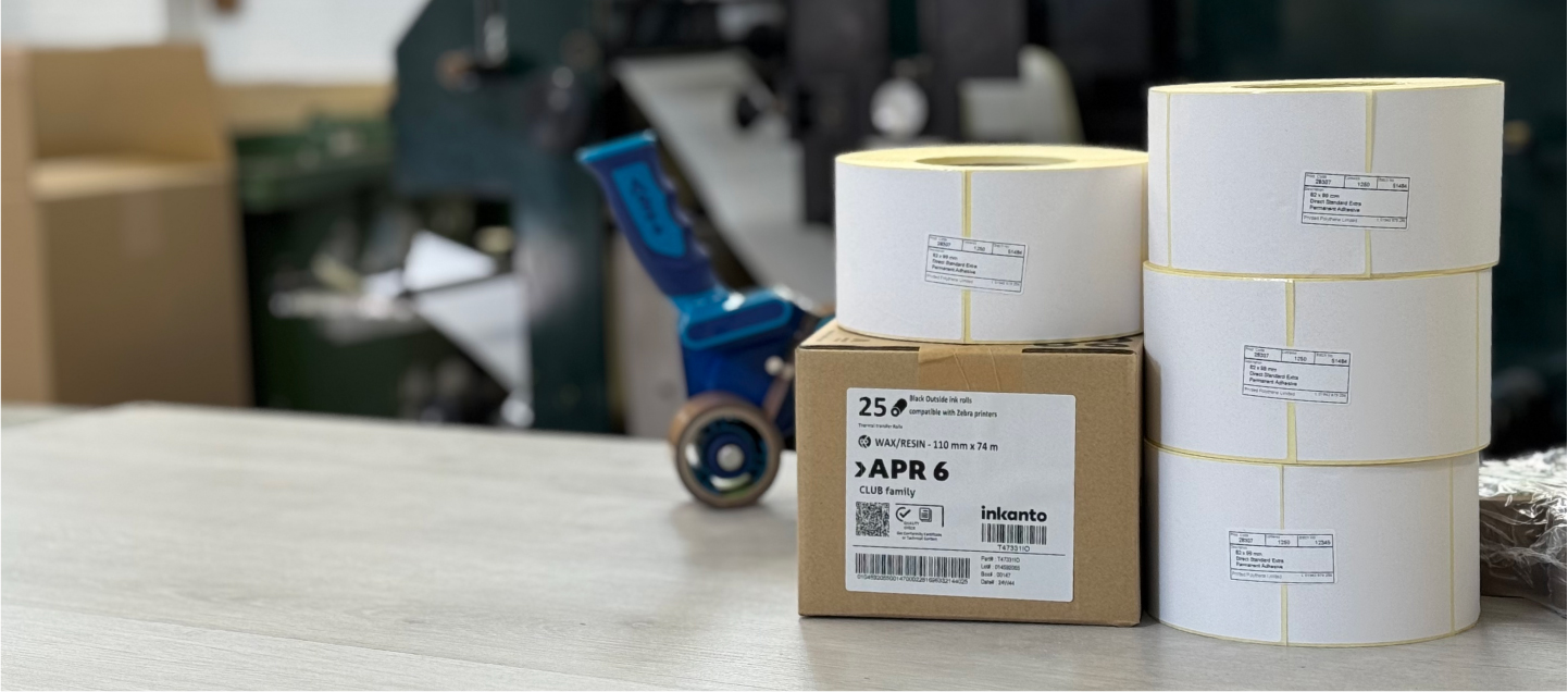 Rolls of thermal transfer labels and ribbons ready for printing on a workbench